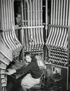 Young woman working a pneumatic tube cash carrier at Marshalls department store, date unknown, public domain